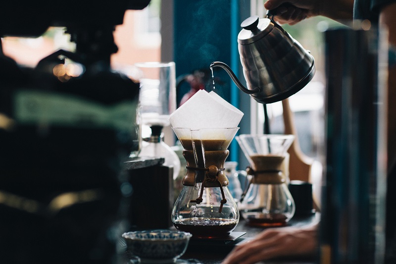 A coffee shop business pours a coffee using a Chemex