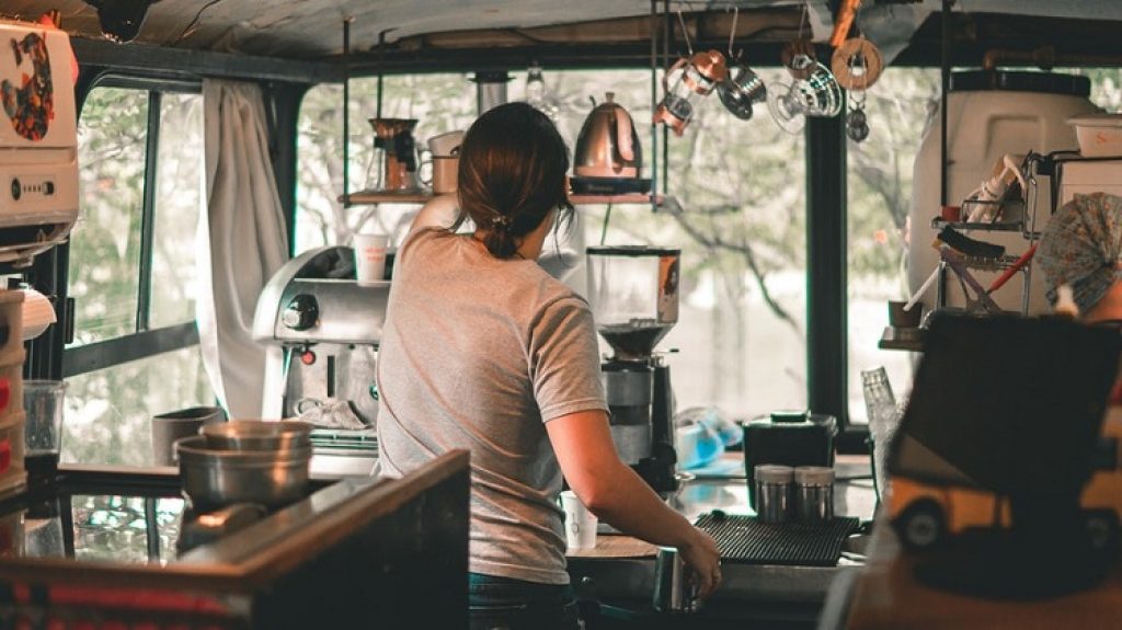 a barista serves coffee in a coffee trailer