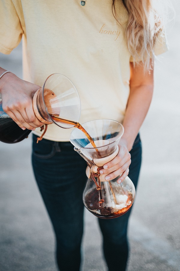 a barista pours coffee from a chemex coffee brewer