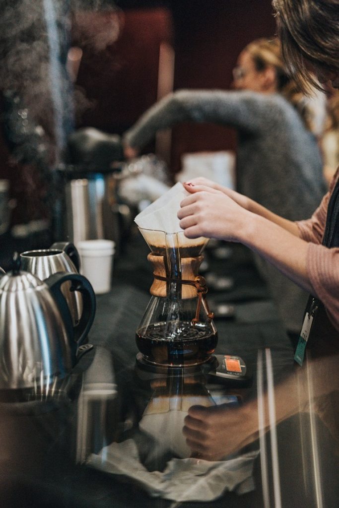 a barista brews coffee on a chemex after writing her business plan.