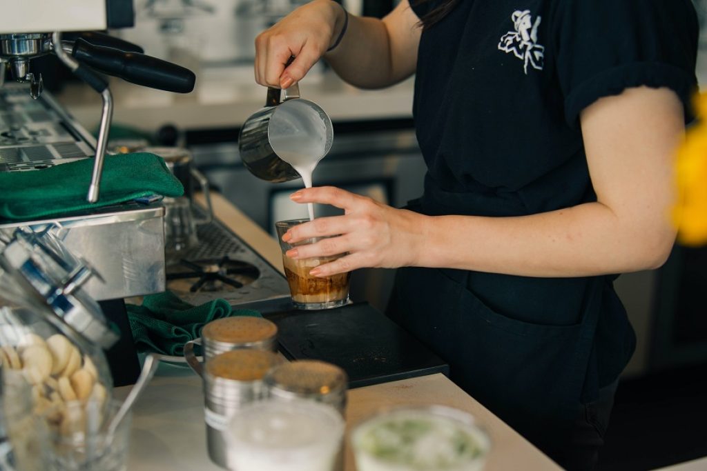a barista pours milk into a coffee
