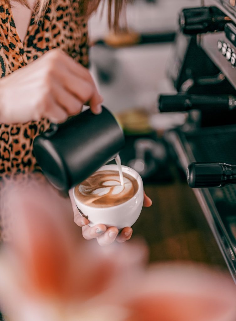 A barista pours a latte for customers at a coffee shop