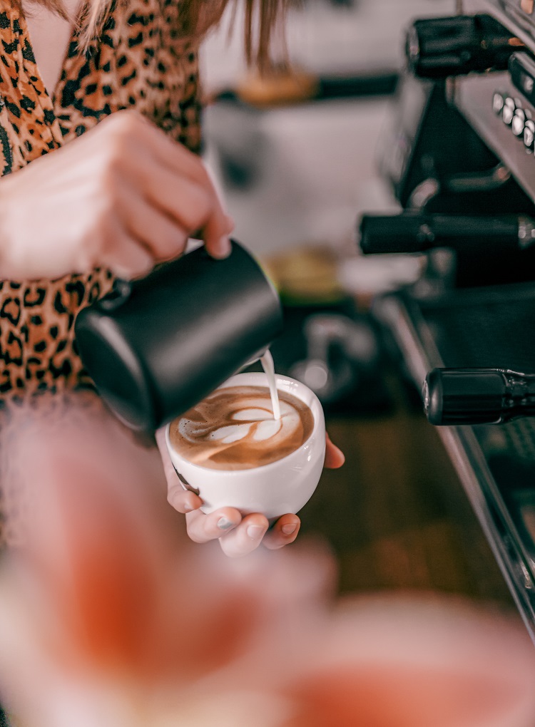 A barista pours a latte in a coffee shop. 