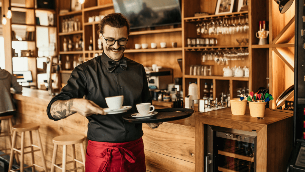 A barista and coffee shop owner serves coffee.
