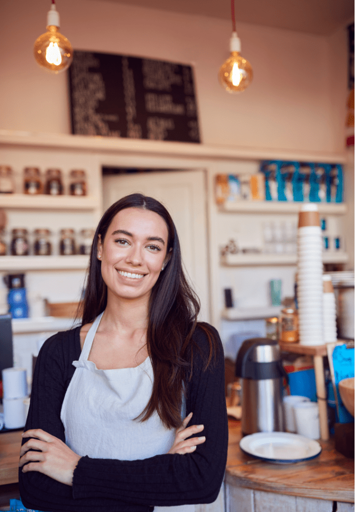 A coffee shop owner smiles at her customer after writing a coffee shop business plan.
