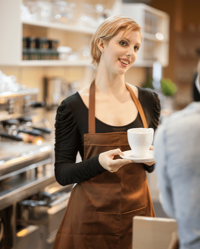 A barista coffee shop owner serves coffee.