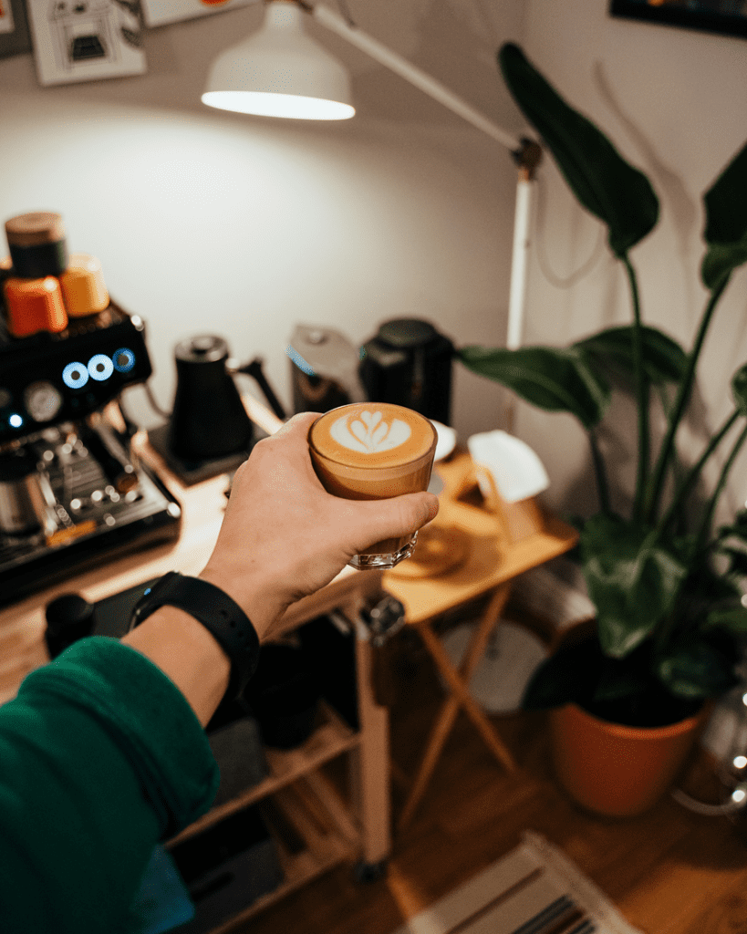 A home-based coffee shop owner holds up a beautiful latte with latte art.