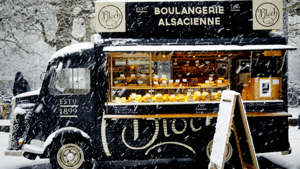 A coffee truck serve coffee in the winter snow.